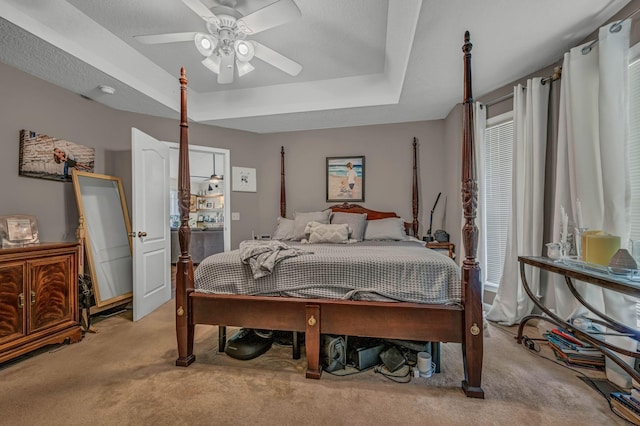 carpeted bedroom with ceiling fan and a raised ceiling