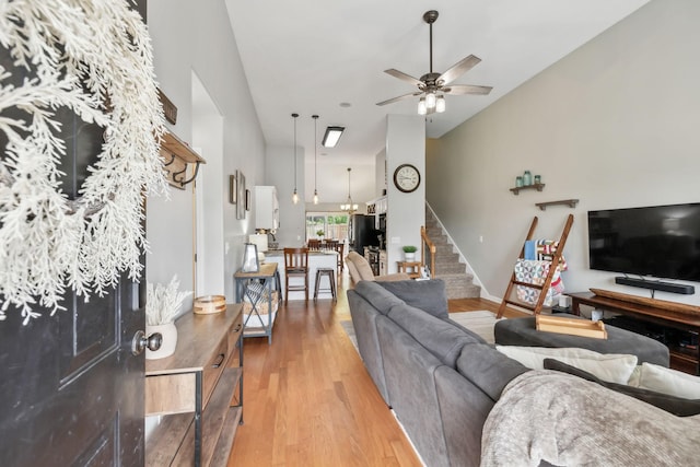 living room with stairway, a ceiling fan, wood finished floors, and vaulted ceiling