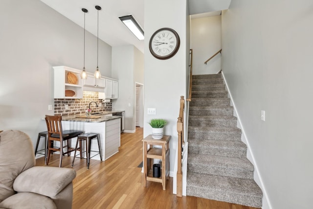 staircase with wood finished floors, high vaulted ceiling, and baseboards