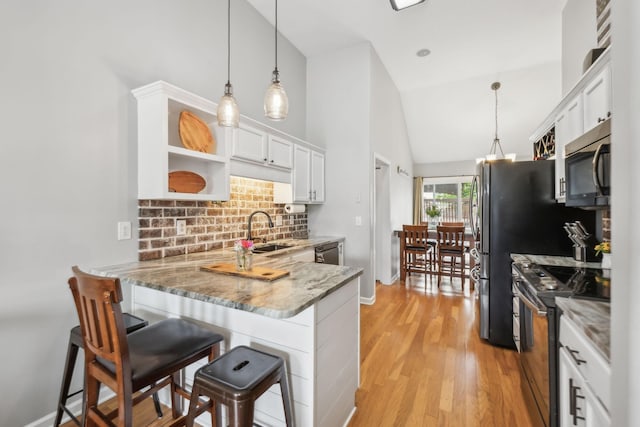 kitchen with stainless steel appliances, tasteful backsplash, white cabinetry, light stone counters, and open shelves