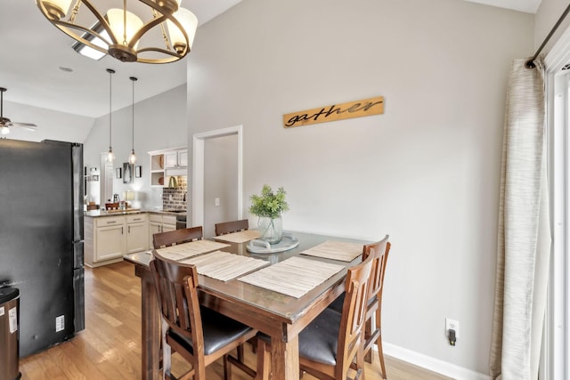 dining space featuring lofted ceiling, light wood-style floors, a chandelier, and a ceiling fan