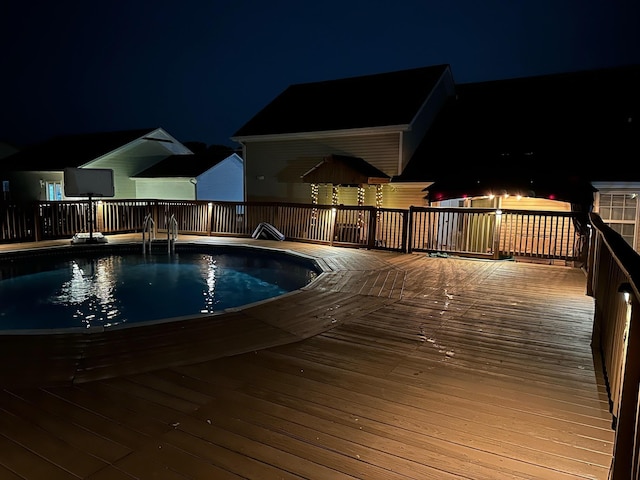 pool at night featuring a deck