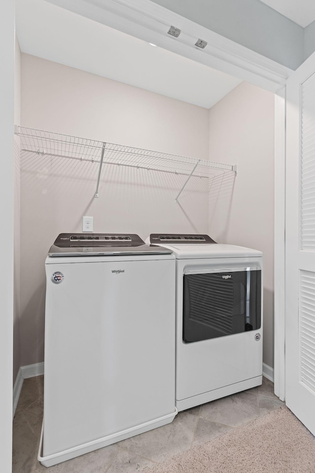 laundry area with washing machine and clothes dryer, baseboards, and light tile patterned flooring