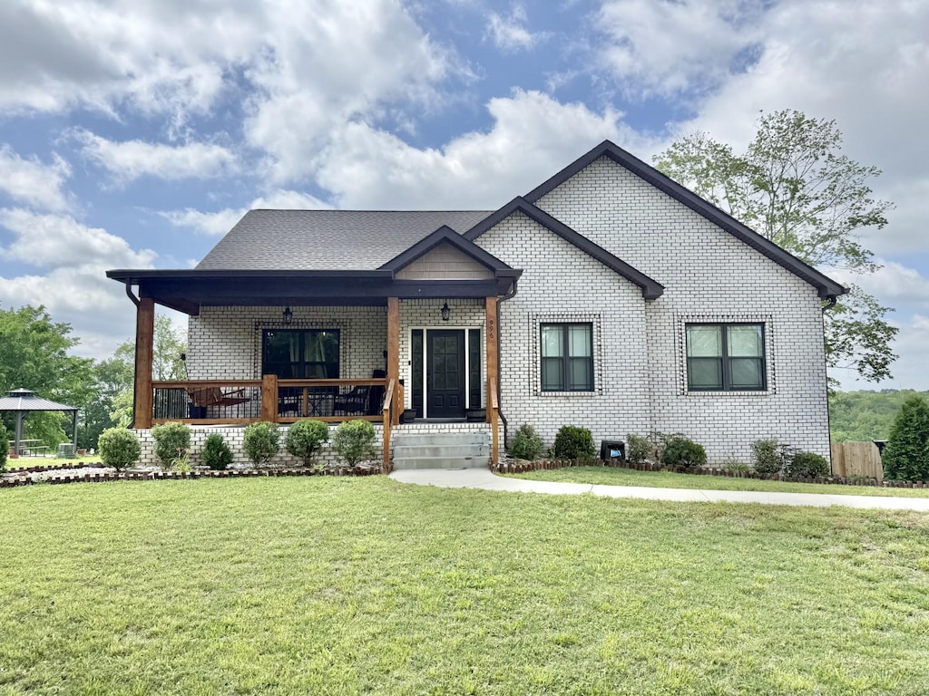 view of front of property with brick siding, covered porch, and a front yard