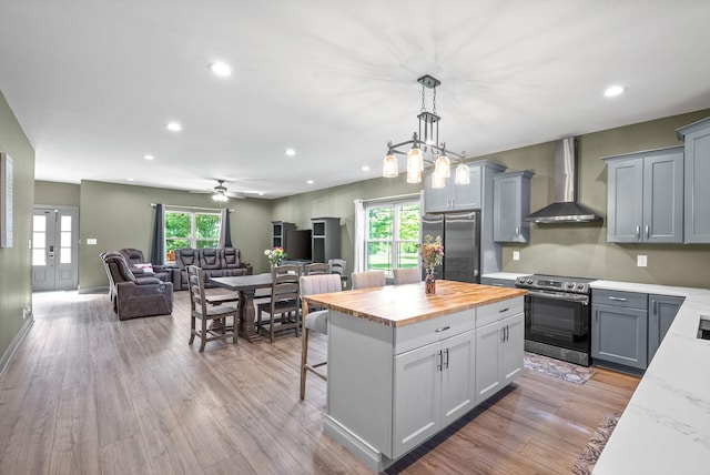 996 Gratton Rd, Clarksville, TN 37043 - kitchen with wall chimney range hood, appliances with stainless steel finishes, butcher block countertops, plenty of natural light, and recessed lighting