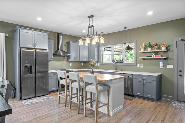 996 Gratton Rd, Clarksville, TN 37043 - kitchen with appliances with stainless steel finishes, wall chimney range hood, a sink, gray cabinetry, and light wood-style flooring