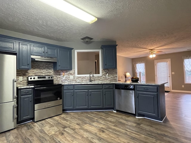 9104 Eddystone Ct, Smyrna, TN 37167 - kitchen featuring stainless steel appliances, under cabinet range hood, a textured ceiling, a peninsula, and decorative backsplash