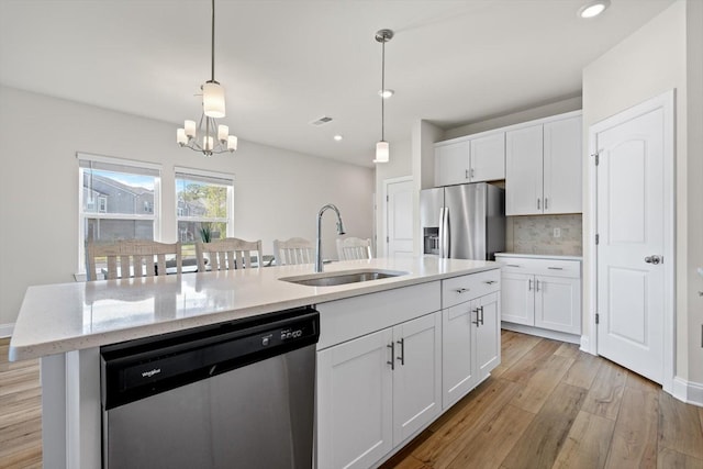 kitchen featuring appliances with stainless steel finishes, a sink, a chandelier, white cabinetry, and light wood finished floors