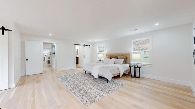 bedroom with a barn door, light wood-type flooring, baseboards, and recessed lighting
