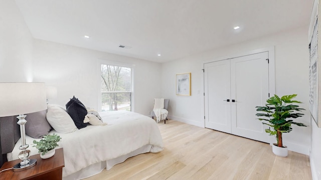 bedroom with light wood finished floors, baseboards, recessed lighting, and a closet