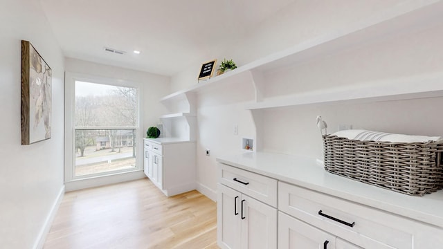 interior space with hookup for an electric dryer, cabinet space, hookup for a washing machine, baseboards, and light wood-type flooring