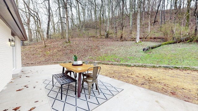 view of patio / terrace with a wooded view and outdoor dining area