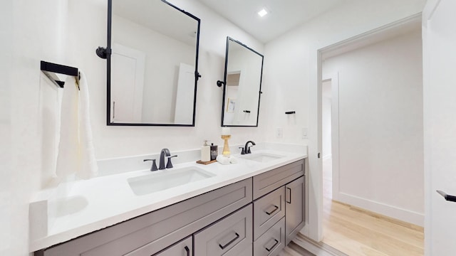 bathroom with wood finished floors, double vanity, and baseboards