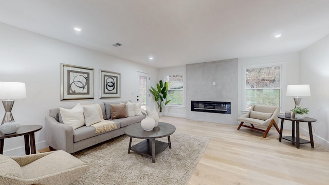 living room featuring plenty of natural light, wood finished floors, recessed lighting, a fireplace, and baseboards