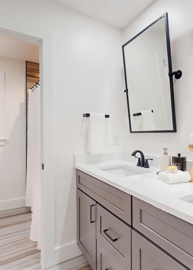 full bath with baseboards, vanity, and wood finished floors