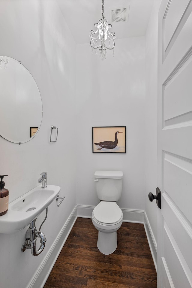 bathroom featuring a chandelier, wood finished floors, baseboards, and toilet