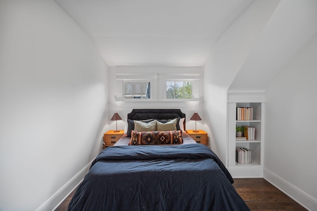 bedroom featuring wood finished floors, lofted ceiling, and baseboards