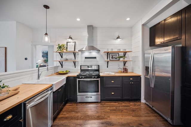 kitchen featuring stainless steel appliances, open shelves, wooden counters, wall chimney range hood, and recessed lighting