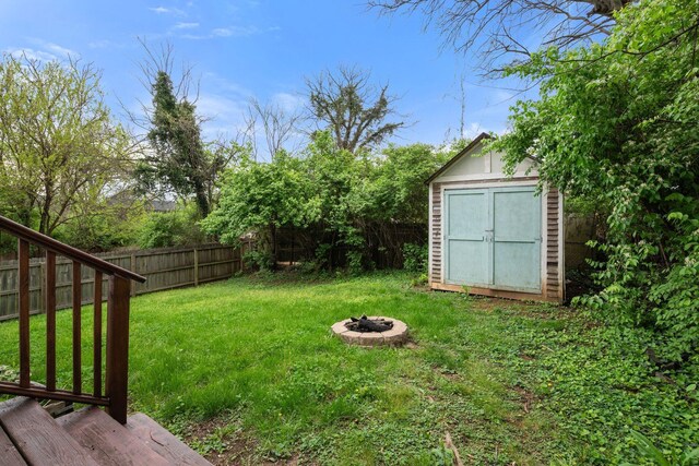 view of yard with a fire pit, a storage unit, and an outdoor structure