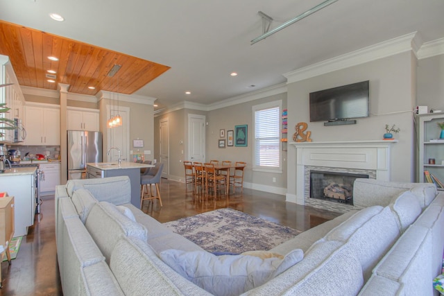living room with recessed lighting, dark wood finished floors, a stone fireplace, crown molding, and baseboards
