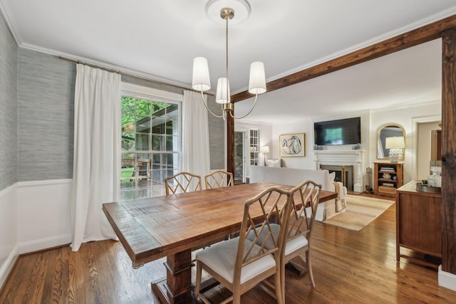 dining area featuring ornamental molding, wood finished floors, a fireplace, a chandelier, and baseboards