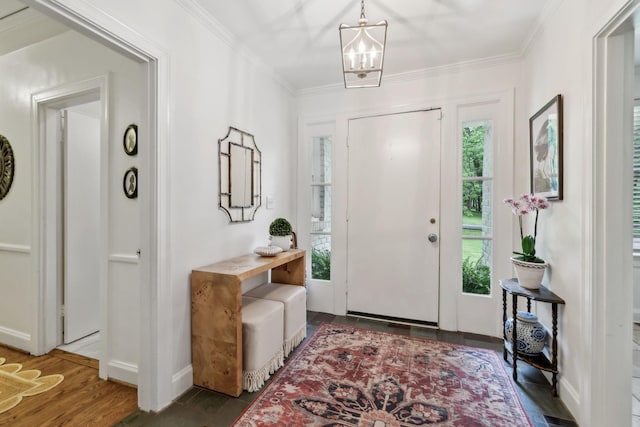 foyer entrance with a chandelier, crown molding, baseboards, and wood finished floors