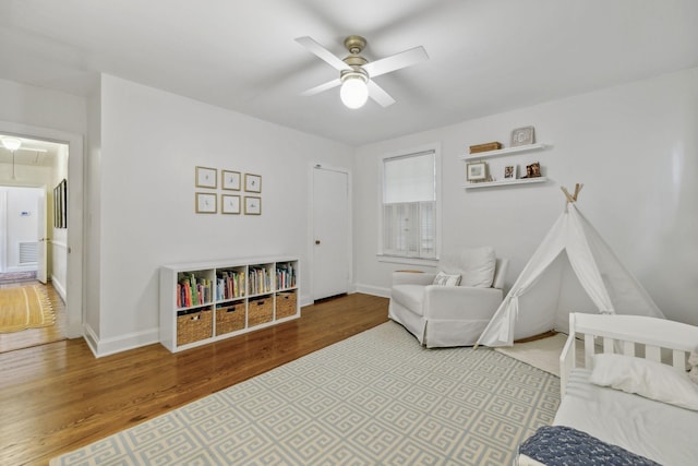 bedroom featuring attic access, wood finished floors, baseboards, and a ceiling fan
