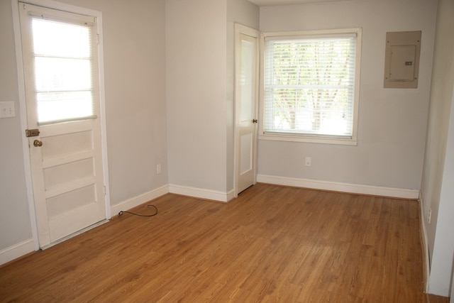 unfurnished room with electric panel, baseboards, and light wood finished floors