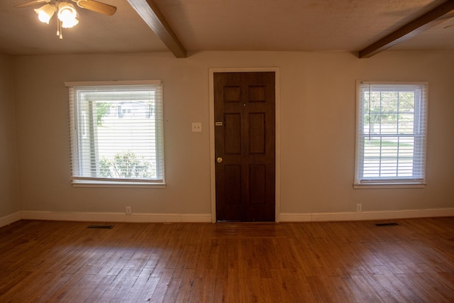 spare room featuring beam ceiling, hardwood / wood-style floors, baseboards, and ceiling fan