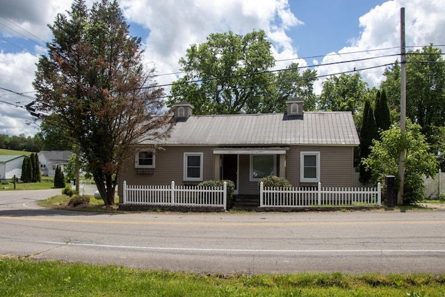 ranch-style home with metal roof and a fenced front yard