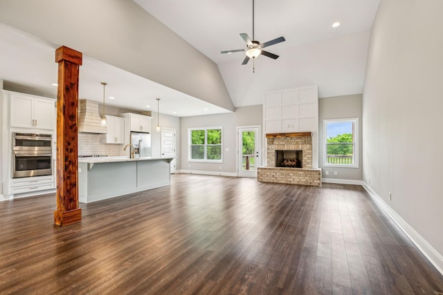 7575 Carthage Hwy, Lebanon, TN 37087 - unfurnished living room with dark wood-style floors, ceiling fan, baseboards, a brick fireplace, and high vaulted ceiling