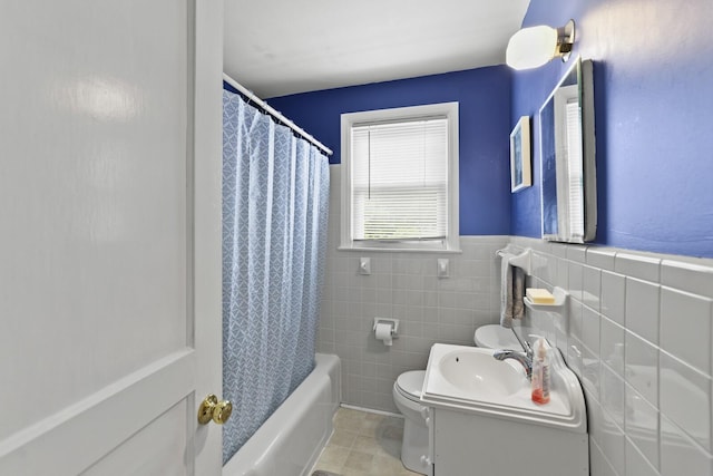 full bathroom featuring toilet, tile walls, tile patterned flooring, vanity, and a wainscoted wall