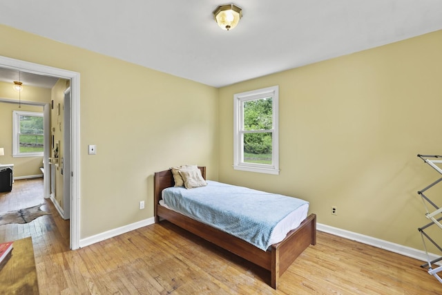 bedroom with wood finished floors, multiple windows, and baseboards