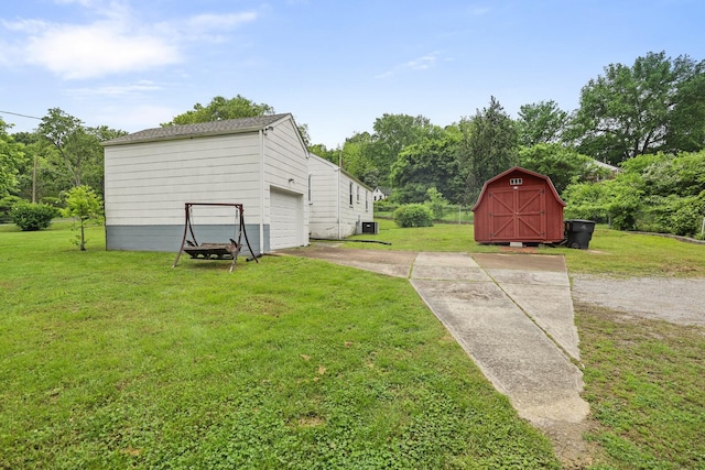 view of grassy yard featuring concrete driveway, an attached garage, an outdoor structure, and a storage unit