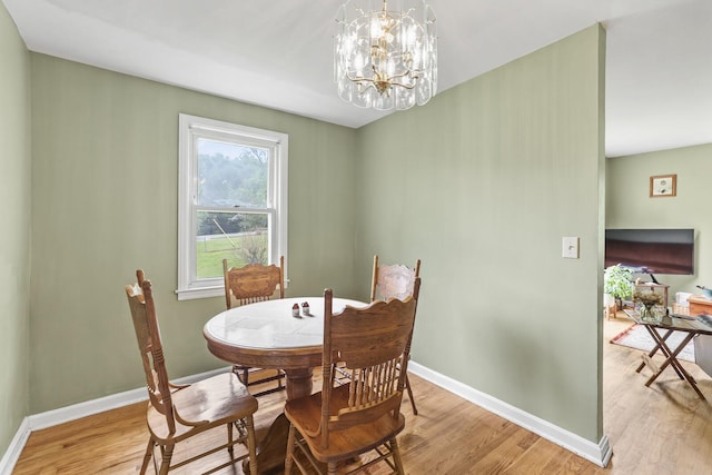 dining space featuring light wood finished floors, a chandelier, and baseboards