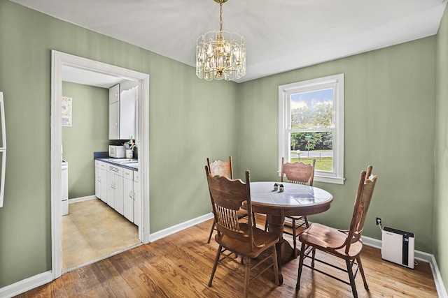 dining space with a chandelier, light wood finished floors, and baseboards