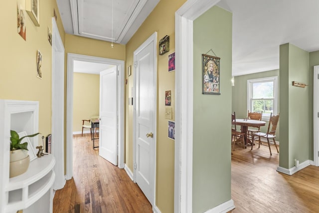 hallway with attic access, wood finished floors, and baseboards