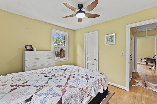 bedroom with attic access, light wood-type flooring, baseboards, and a ceiling fan