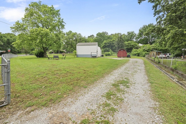 view of yard with driveway, a barn, an outdoor structure, and view of scattered trees