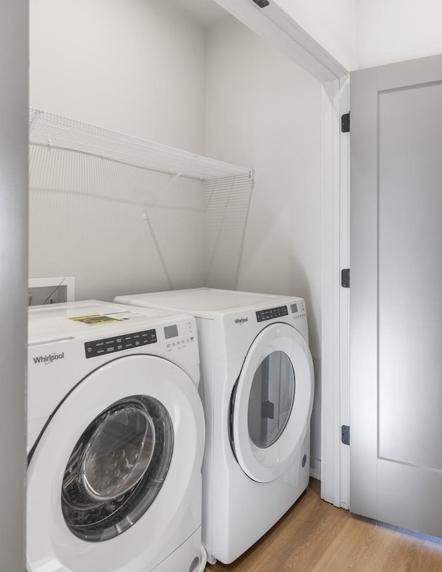 laundry room with washing machine and dryer and light wood-type flooring