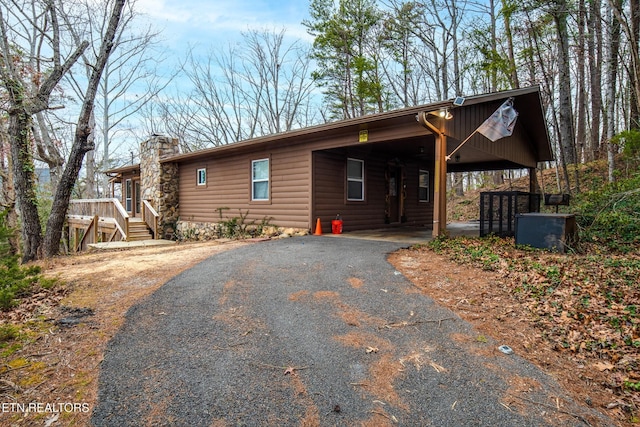 2819 Pine Haven Dr, Sevierville, TN 37862 - view of front facade featuring asphalt driveway, a chimney, an attached carport, and log veneer siding