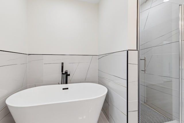full bathroom featuring tile walls, a soaking tub, and a walk in shower