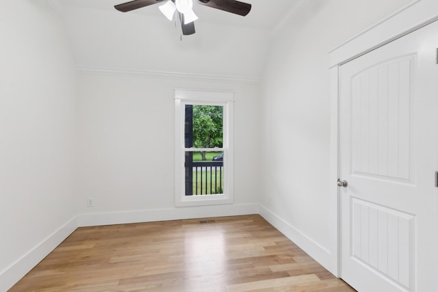 empty room with ceiling fan, crown molding, light wood-style floors, baseboards, and lofted ceiling