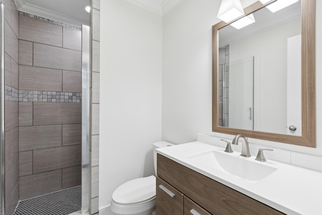 bathroom with toilet, ornamental molding, a tile shower, and vanity
