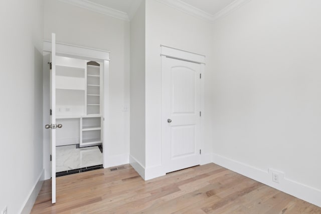unfurnished bedroom featuring light wood-type flooring, crown molding, and baseboards