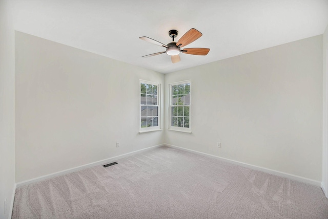 unfurnished room with a ceiling fan, baseboards, and light carpet