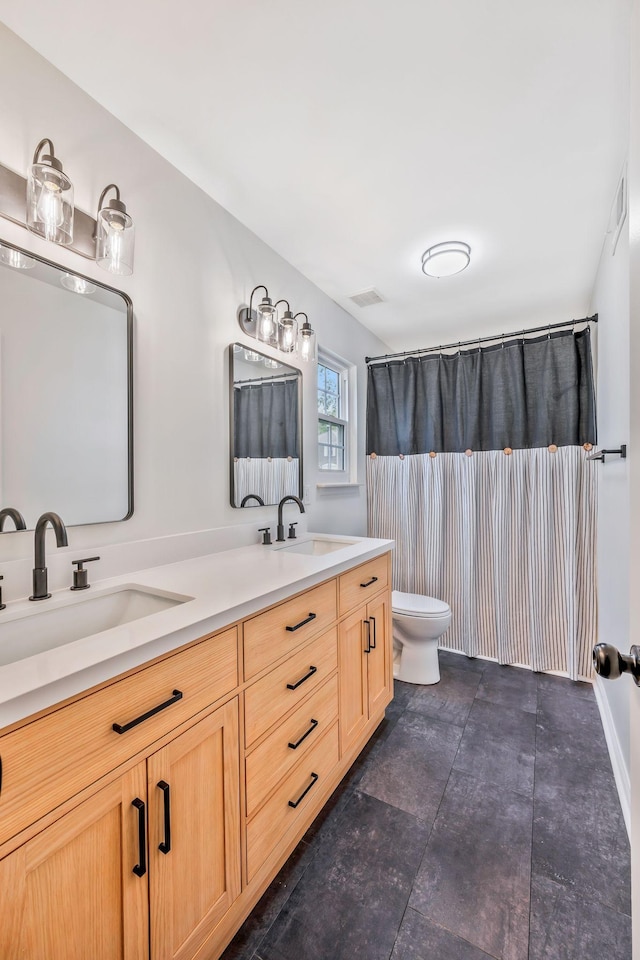 bathroom featuring toilet and double vanity