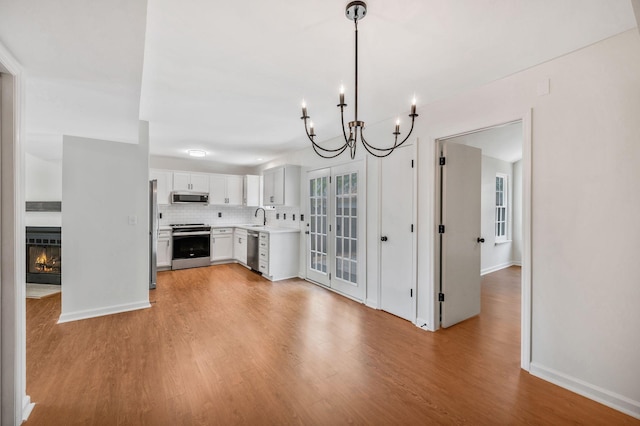 kitchen featuring appliances with stainless steel finishes, a chandelier, a sink, light countertops, and light wood-style floors