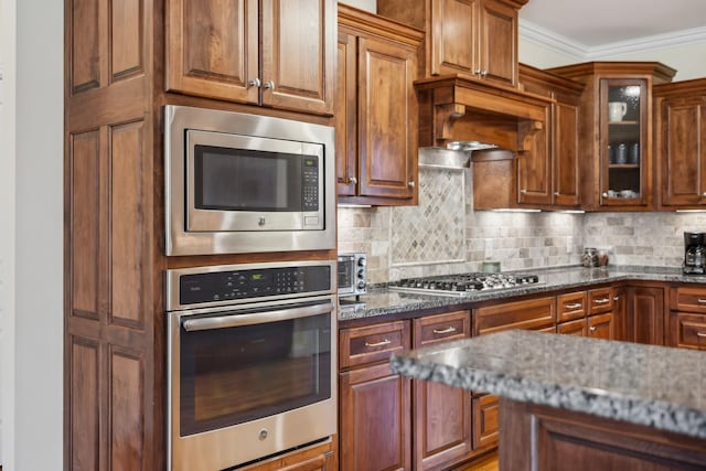 6611 Arno College Grove Rd, College Grove, TN 37046 - kitchen with appliances with stainless steel finishes, stone counters, tasteful backsplash, glass insert cabinets, and crown molding