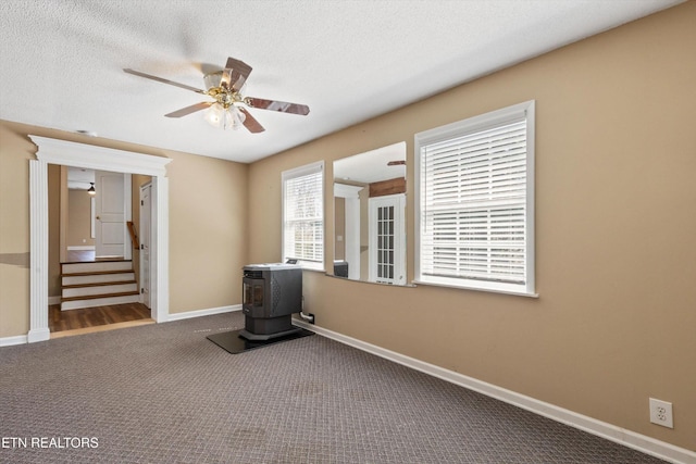 338 Lindsey Mill Cir, Rocky Top, TN 37769 - empty room with a wood stove, ceiling fan, carpet flooring, stairs, and baseboards